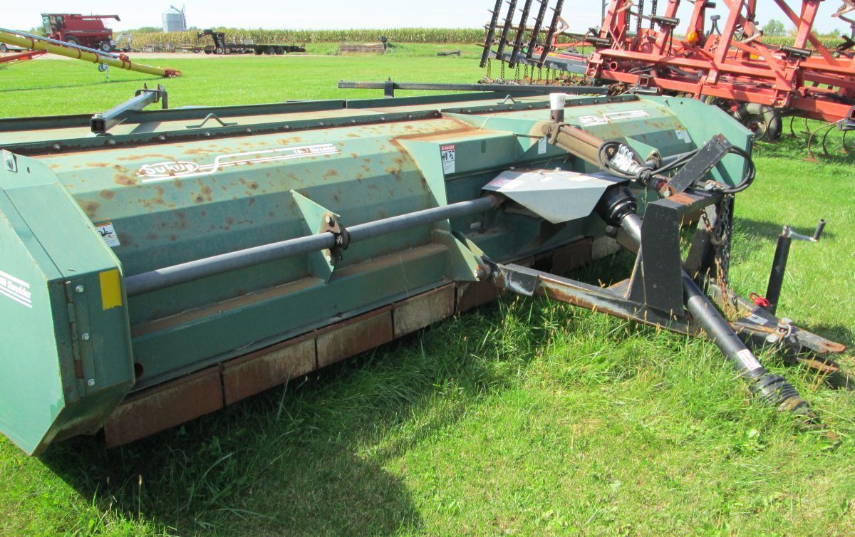 A green machine is sitting on top of a lush green field.