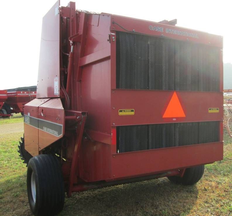 A red tractor with an orange triangle on the side is parked in a field