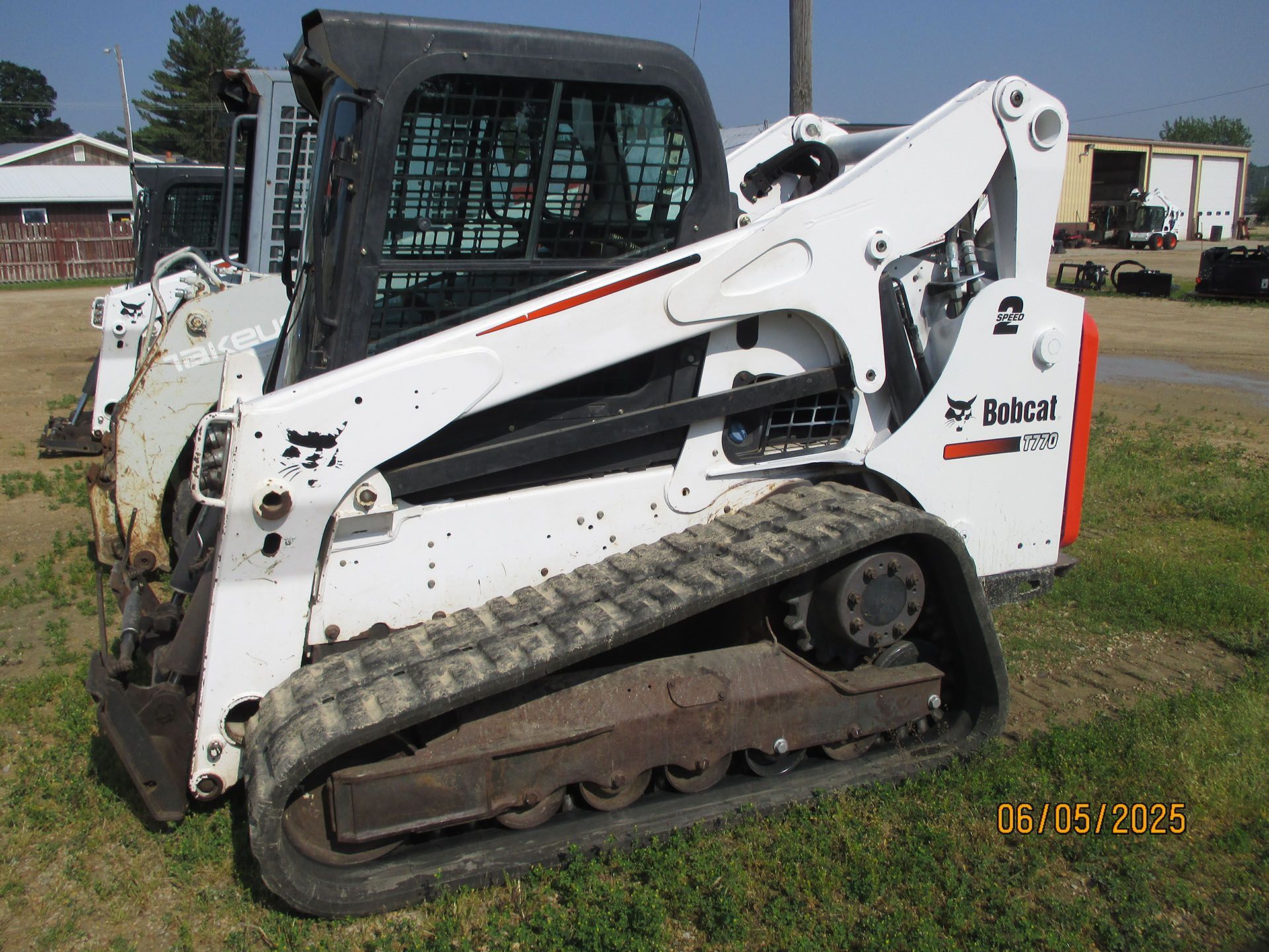 A bobcat tractor is parked in a grassy field