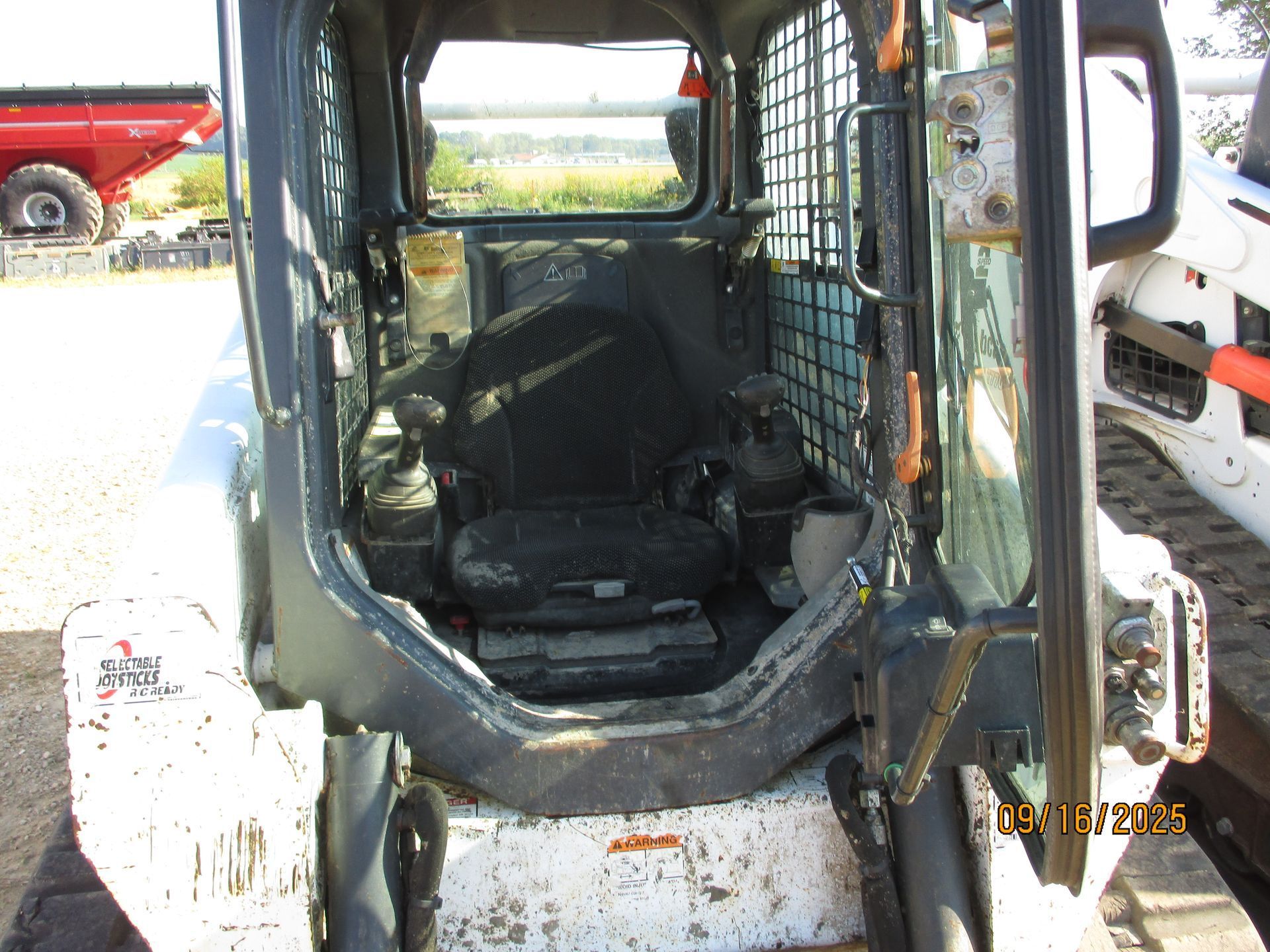 Interior of a Bobcat skid steer loader, showing seat, controls, and safety cage.