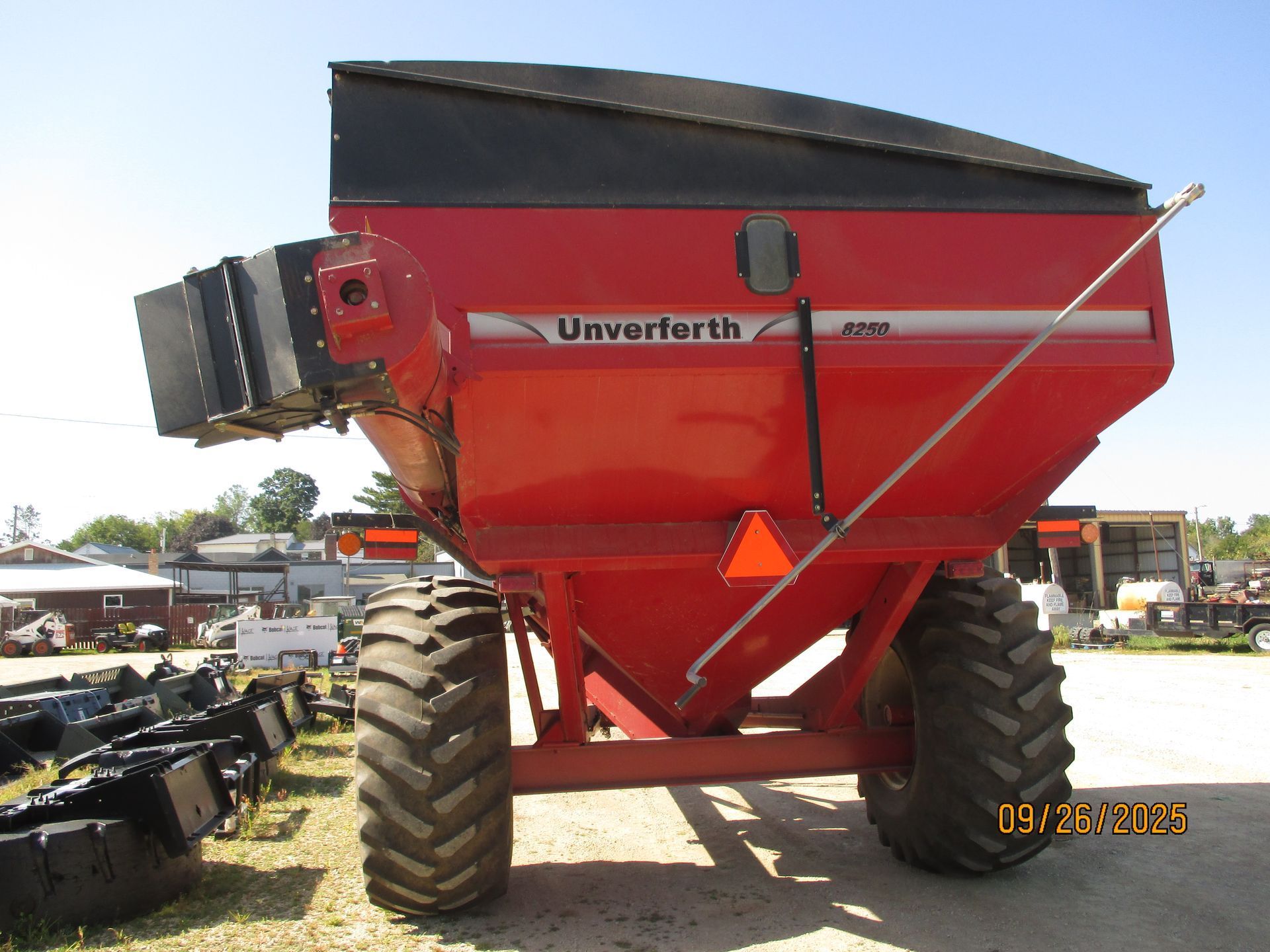 Red Unverferth 5200 grain cart trailer, black top, with large tires in a sunny outdoor setting.