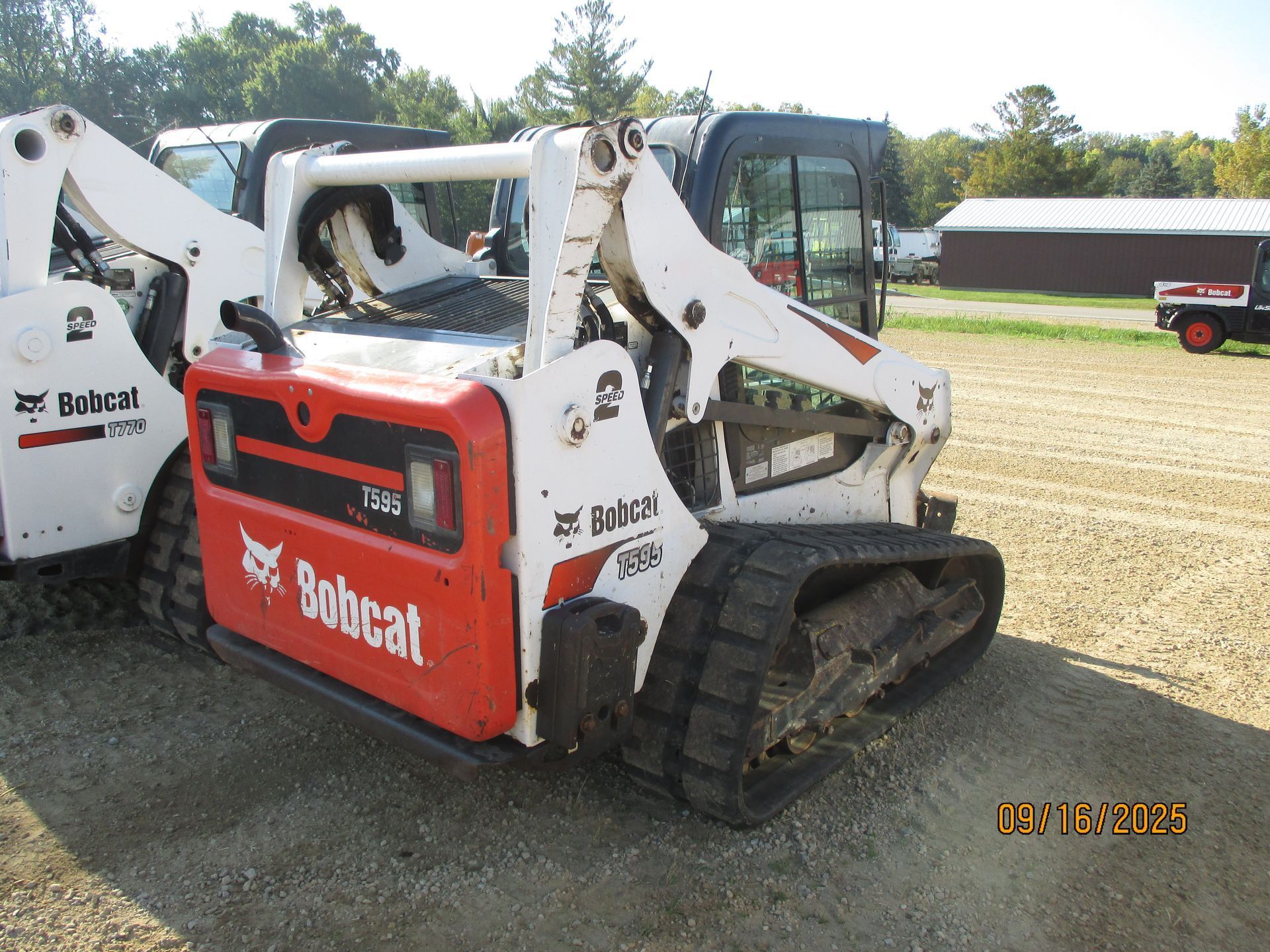 Bobcat T595 compact track loader, white and red, on gravel, outdoors.