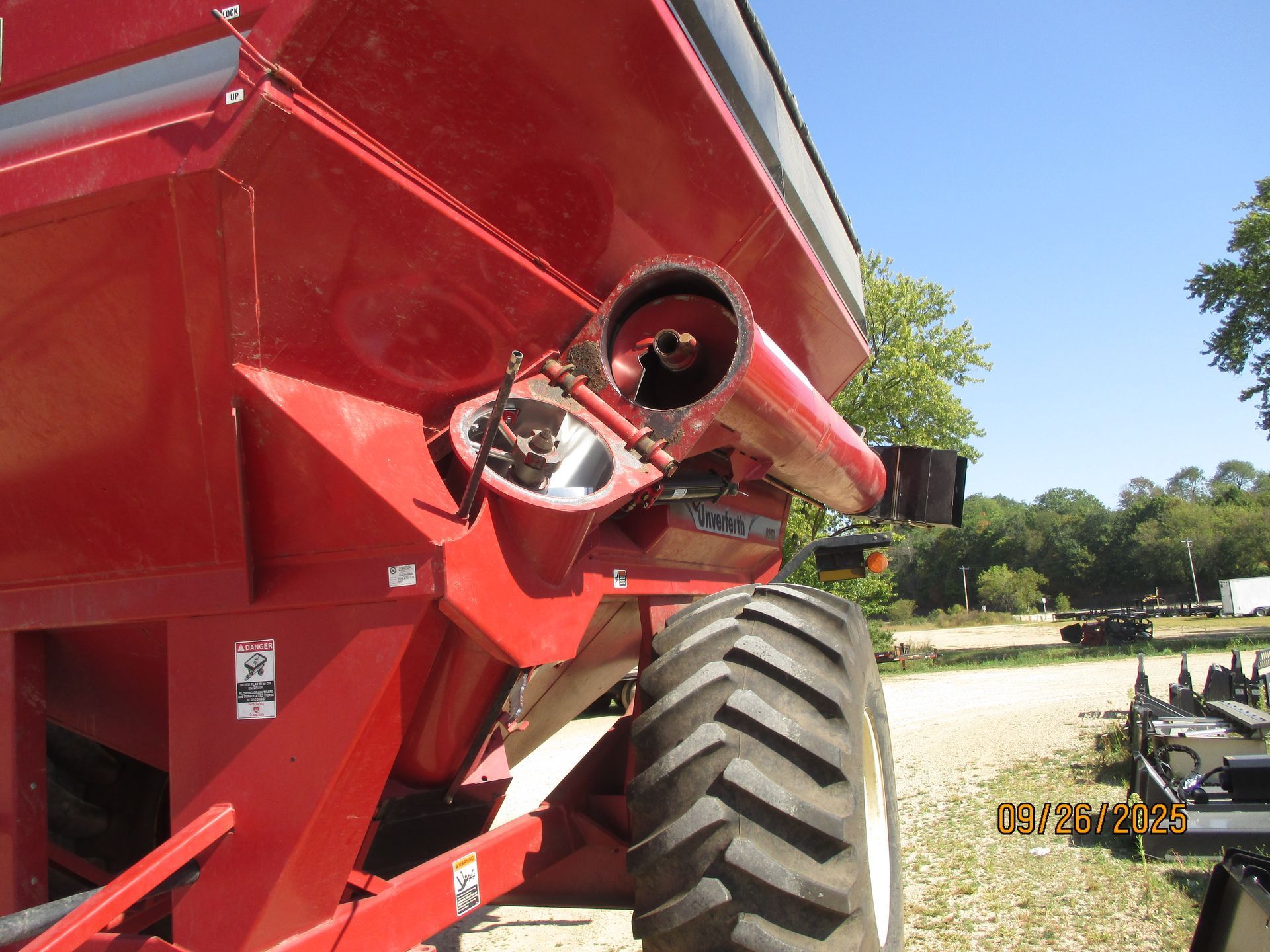 Red grain cart with a broken auger, outdoors.