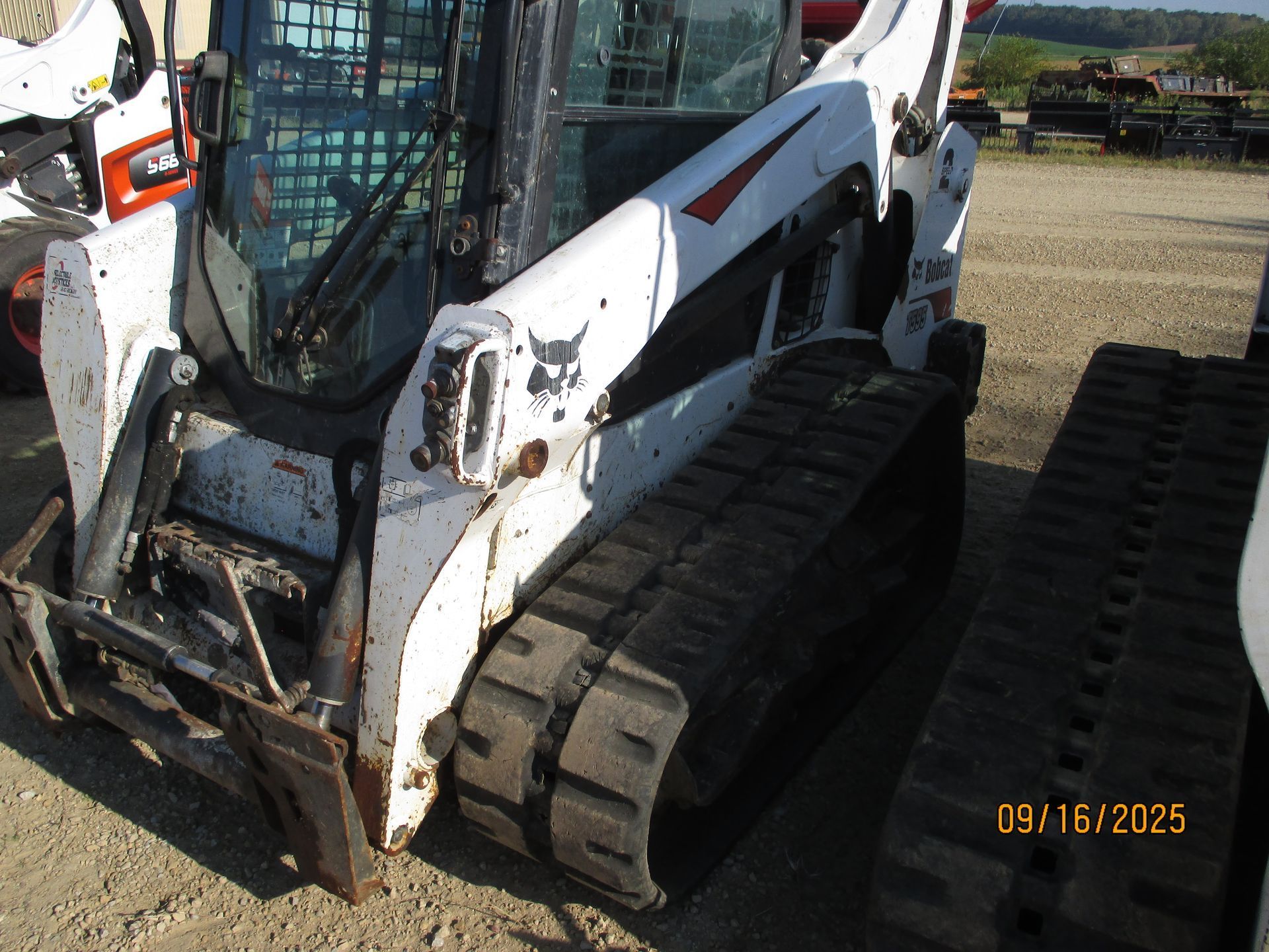 White Bobcat compact track loader with tracks, in an outdoor setting.