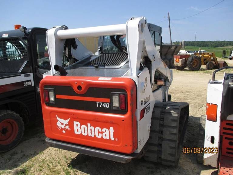 A bobcat tractor is parked in a dirt field
