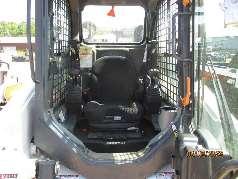 The inside of a bobcat skid steer with a black seat