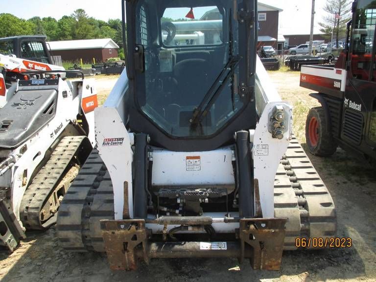A bobcat tractor is parked in a dirt lot