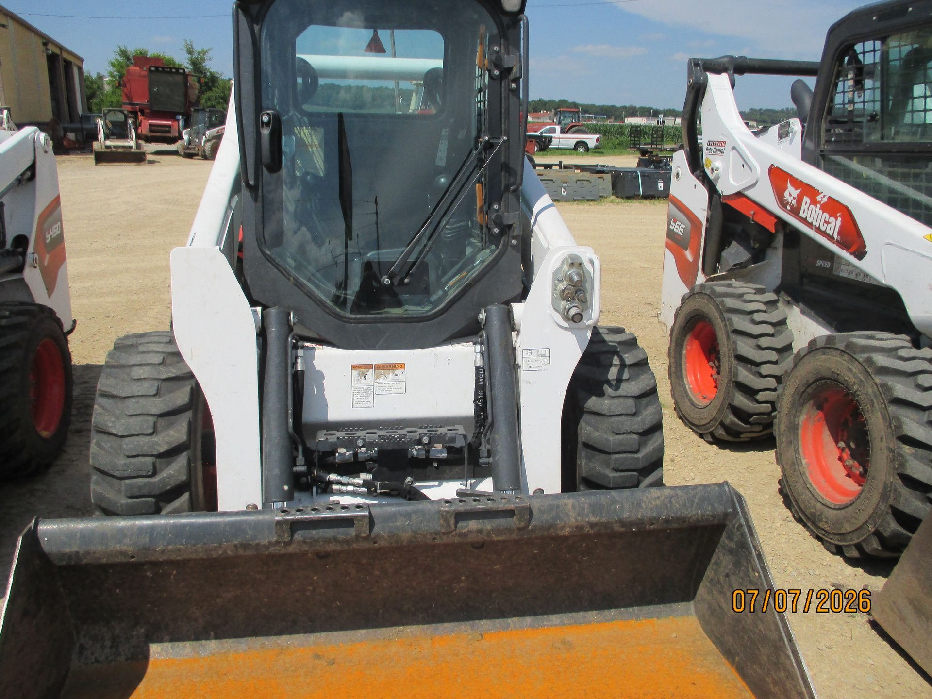 White skid-steer loader with bucket parked outdoors at a construction equipment lot