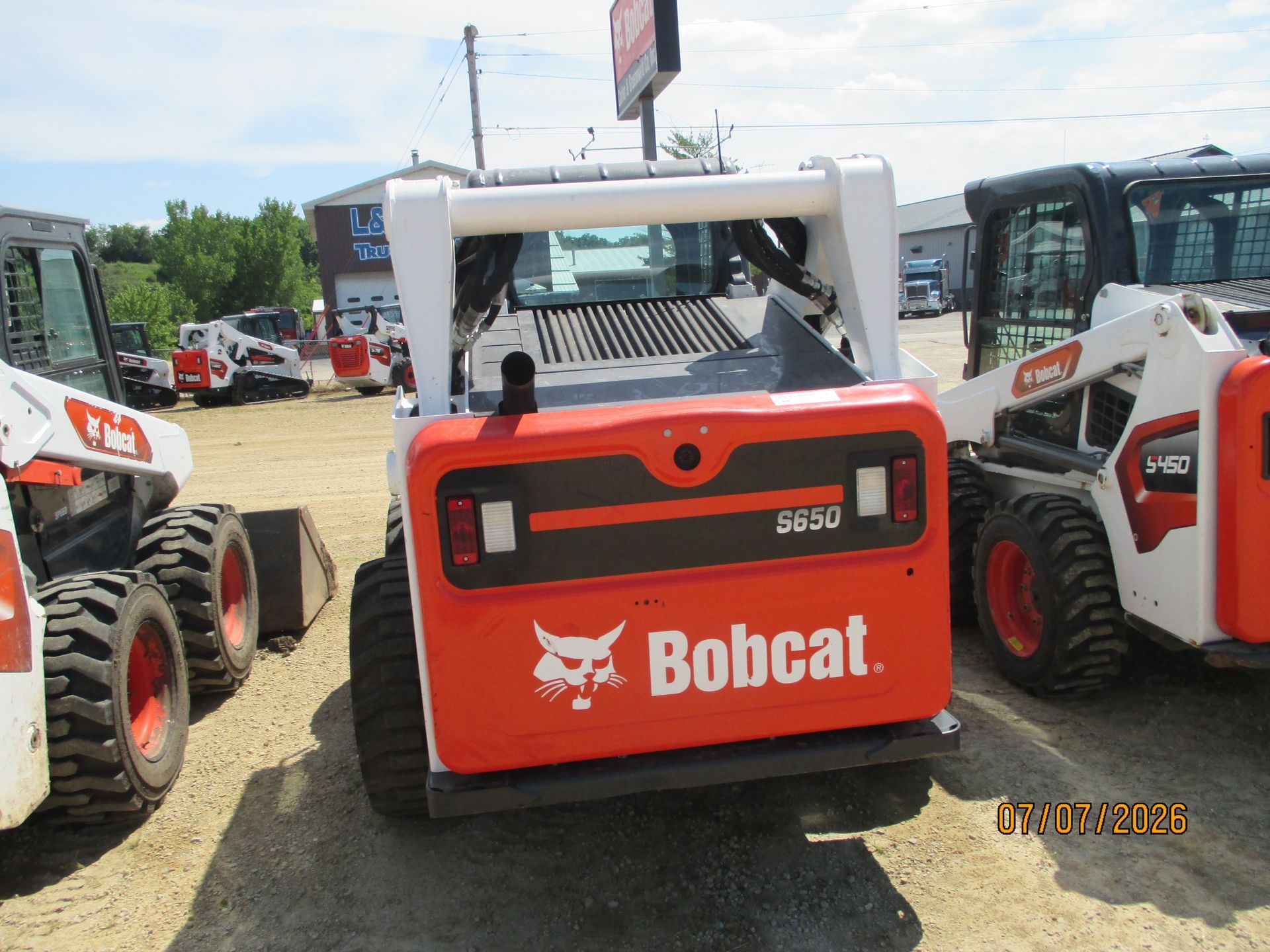 Red Bobcat skid-steer loader parked among other construction machines in a lot