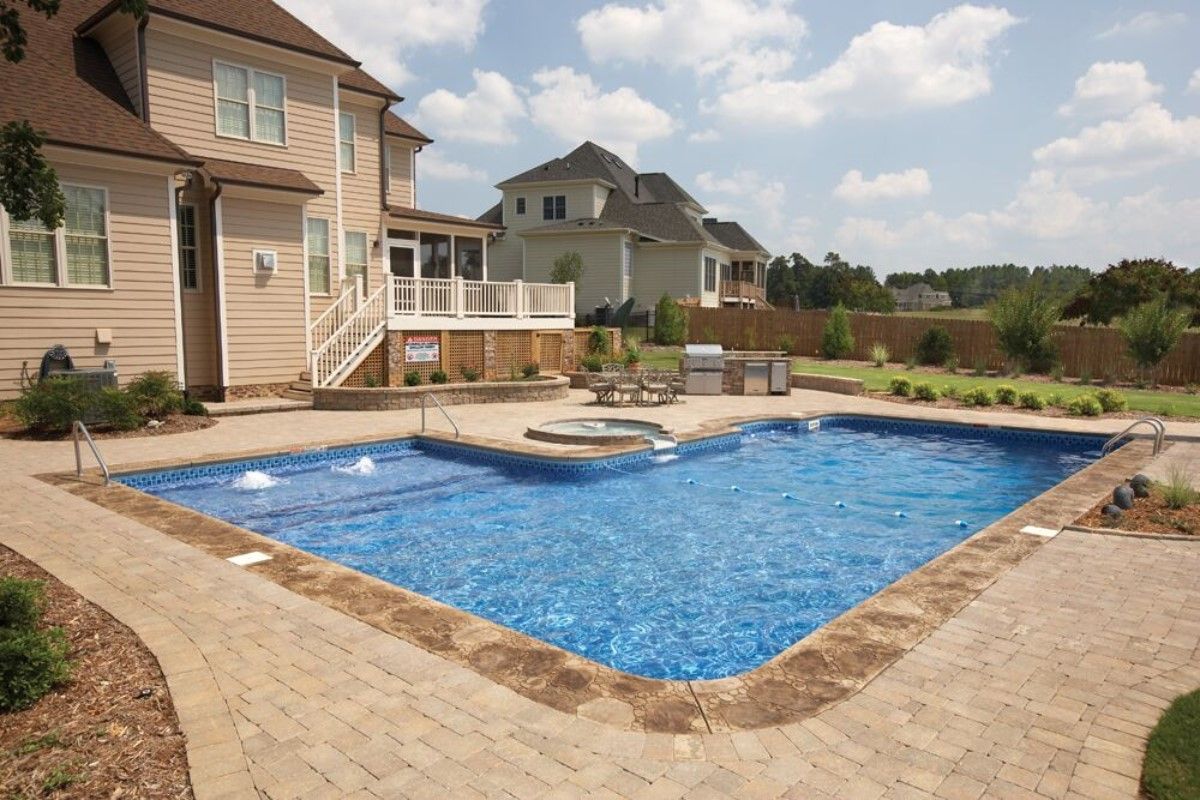 A large swimming pool is in the backyard of a house
