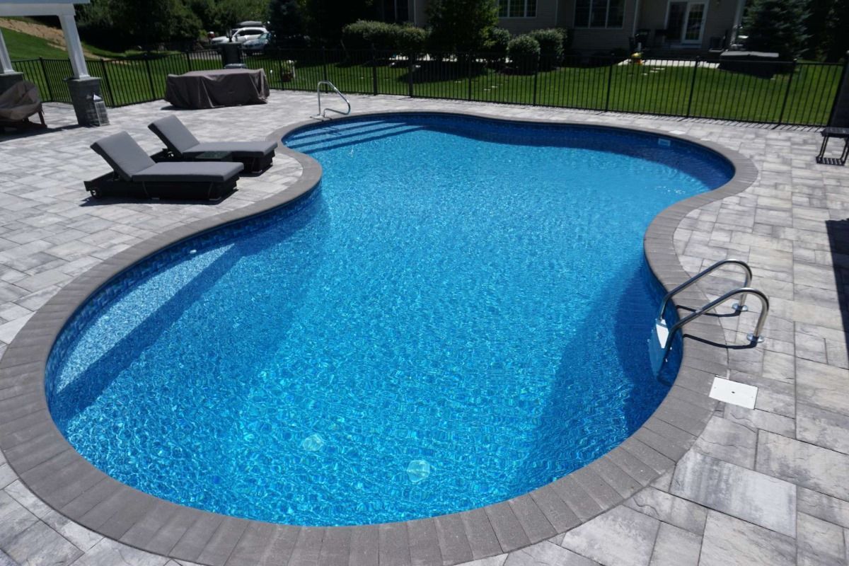 A large swimming pool surrounded by chairs and a fence