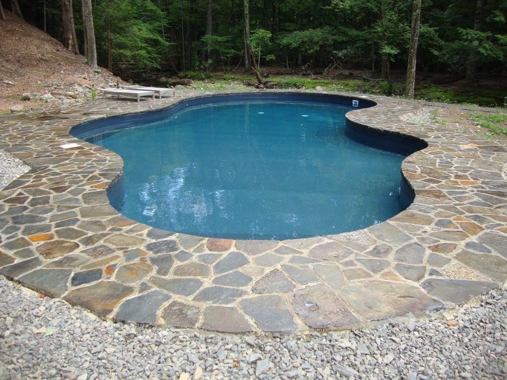 A large swimming pool is surrounded by a stone patio