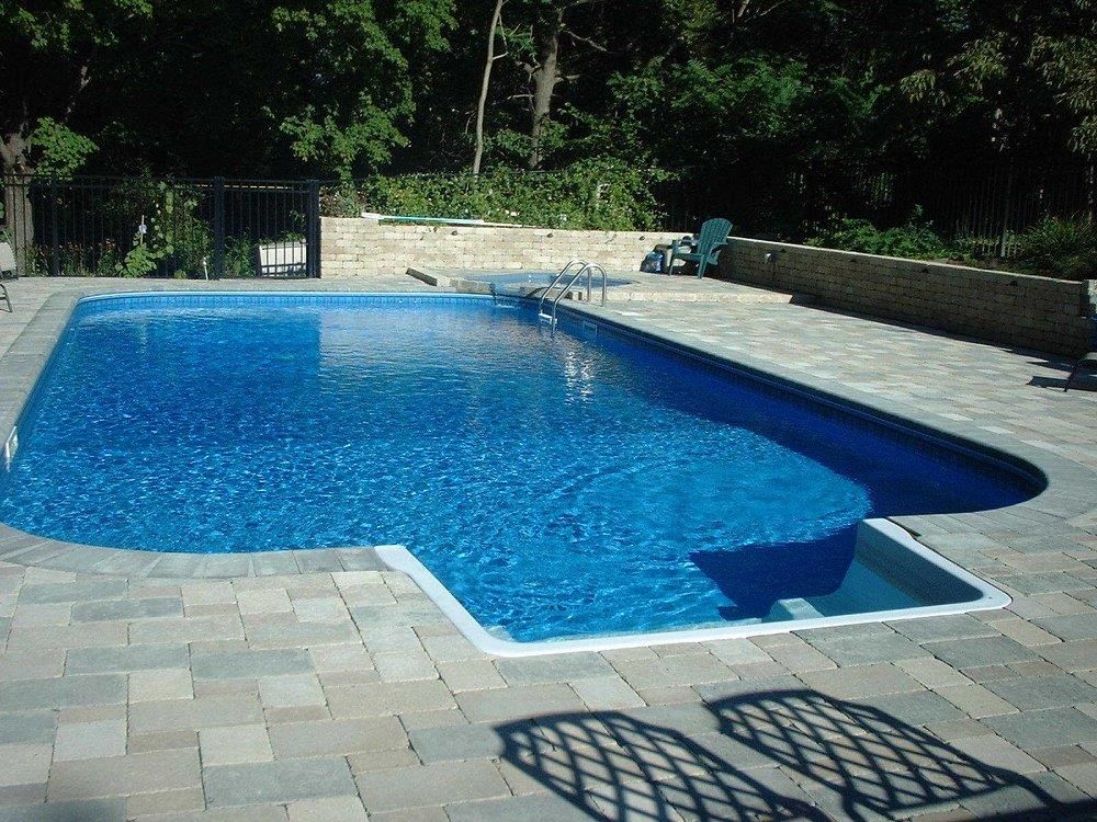 A large swimming pool is surrounded by a brick patio