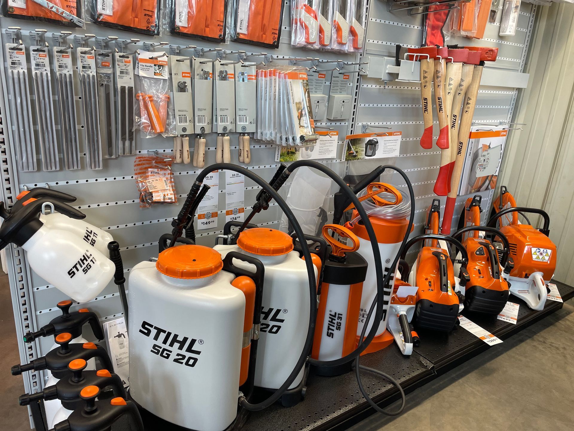 A hardware store display featuring orange and white STIHL tools, including sprayers and axes