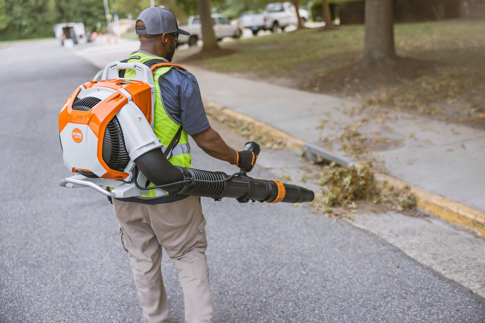 Man uses a STIHL leaf blower on a street, clearing debris