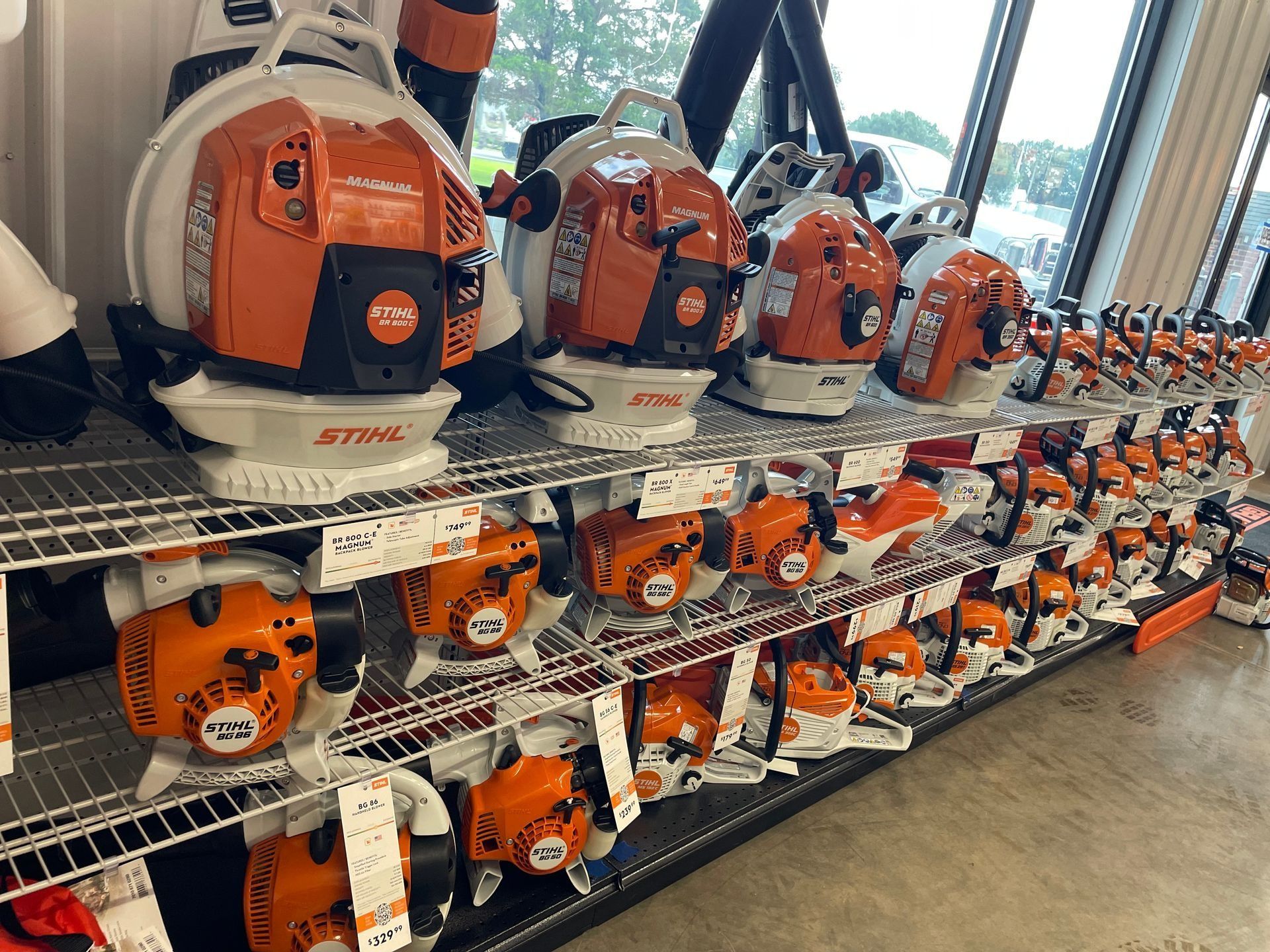 Rows of orange and white Stihl leaf blowers and chainsaws on store shelves.