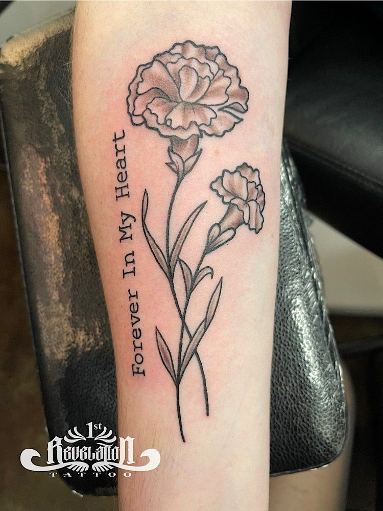 Tattoo of two carnation flowers with the words 