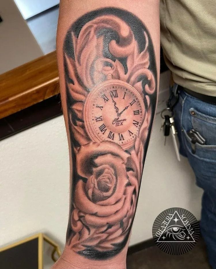 Tattoo of a pocket watch, rose, and ornate leaves on a forearm. Black and white shading.