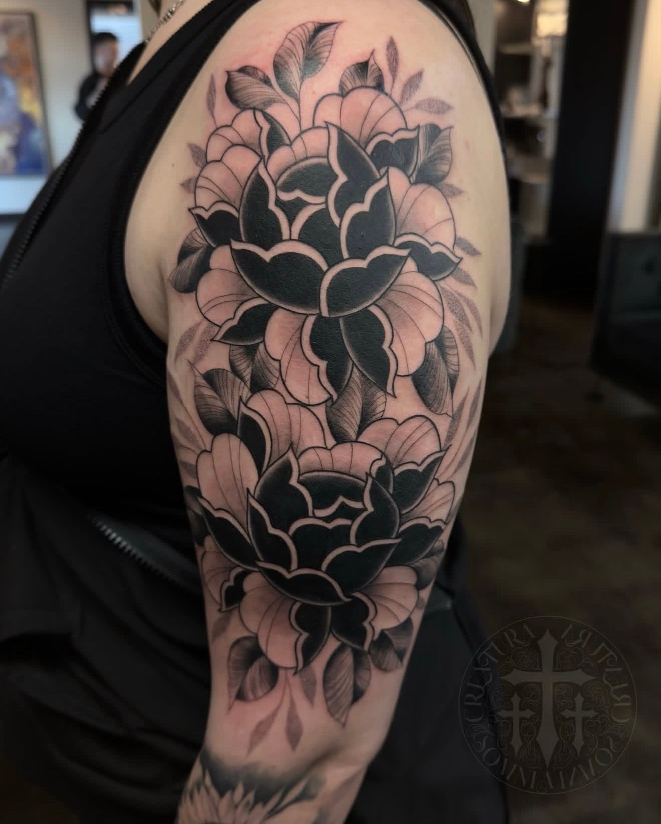 Black-and-gray floral tattoo covering a person’s upper arm and shoulder