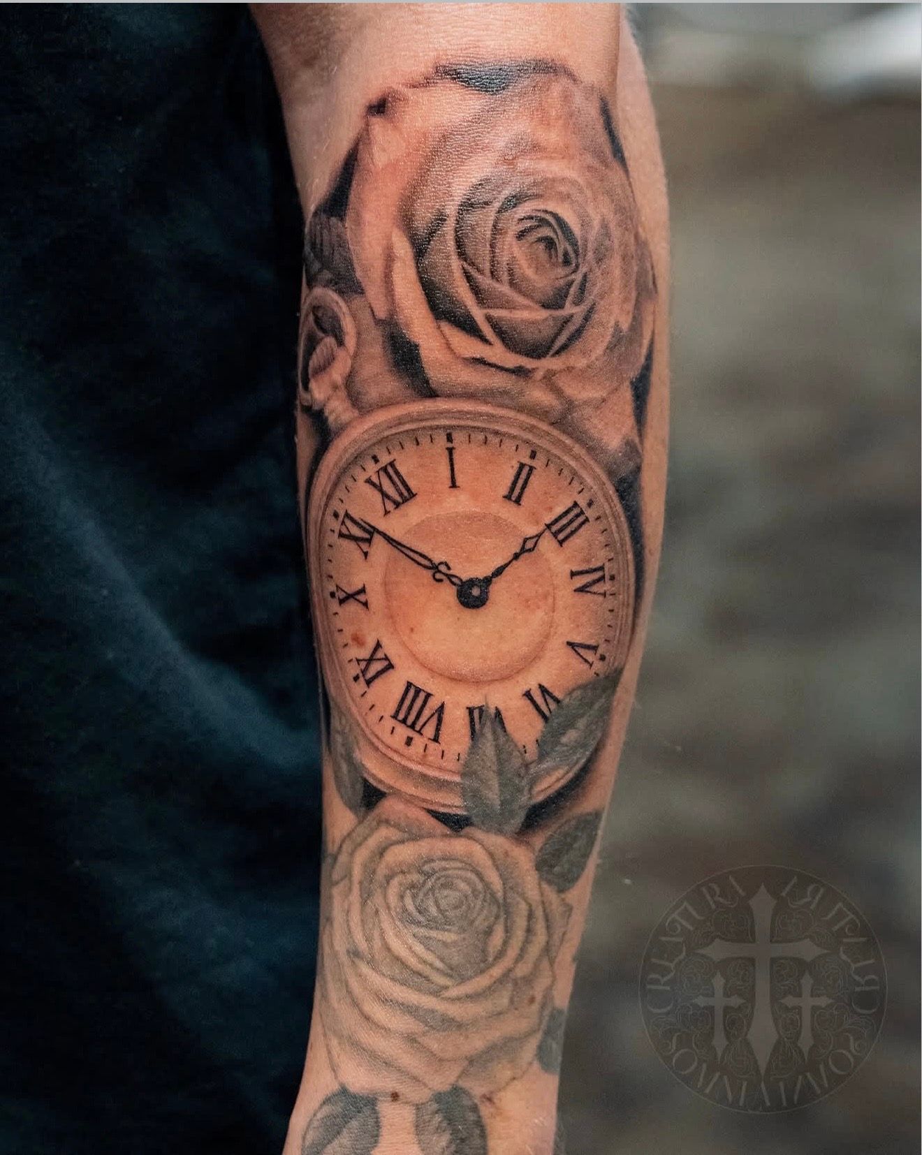 Black and gray tattoo of roses with a clock and Roman numerals on a forearm