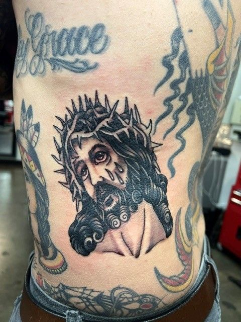 Tattoo on torso: Jesus with a crown of thorns, surrounded by other tattoos.