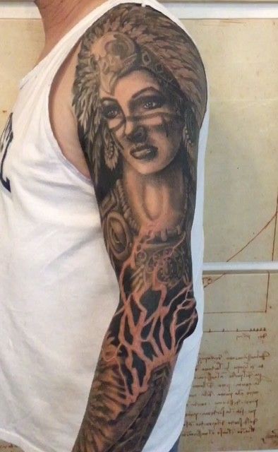 Arm tattoo: woman with Native American headdress, dark colors, detailed artwork.