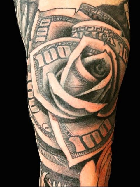 Black and white tattoo of a rose made of hundred dollar bills on a person's arm.