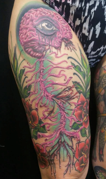 Pink brain tattoo with an eye, vines, and roses on a thigh.