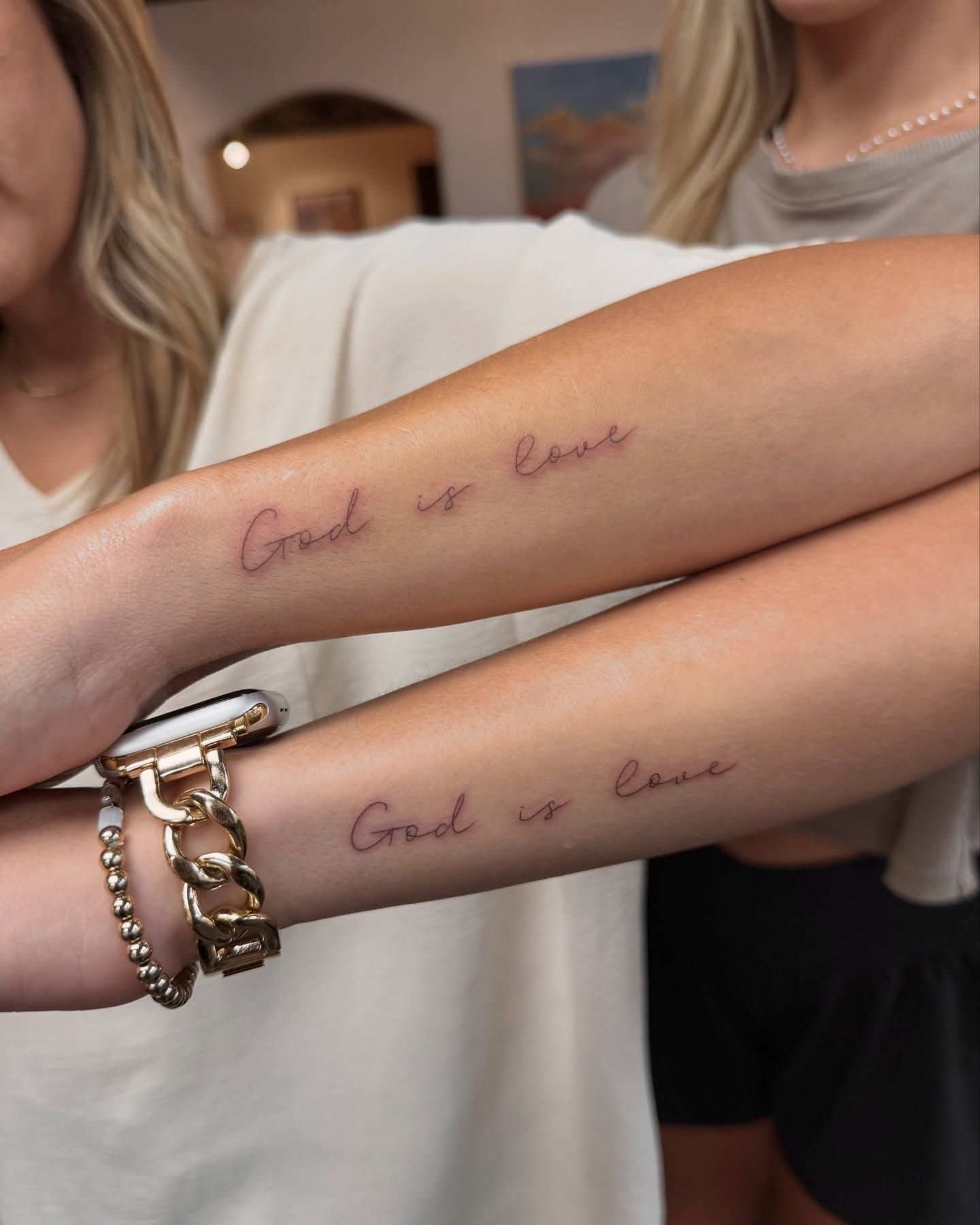 Two arms with matching tattoos that say 