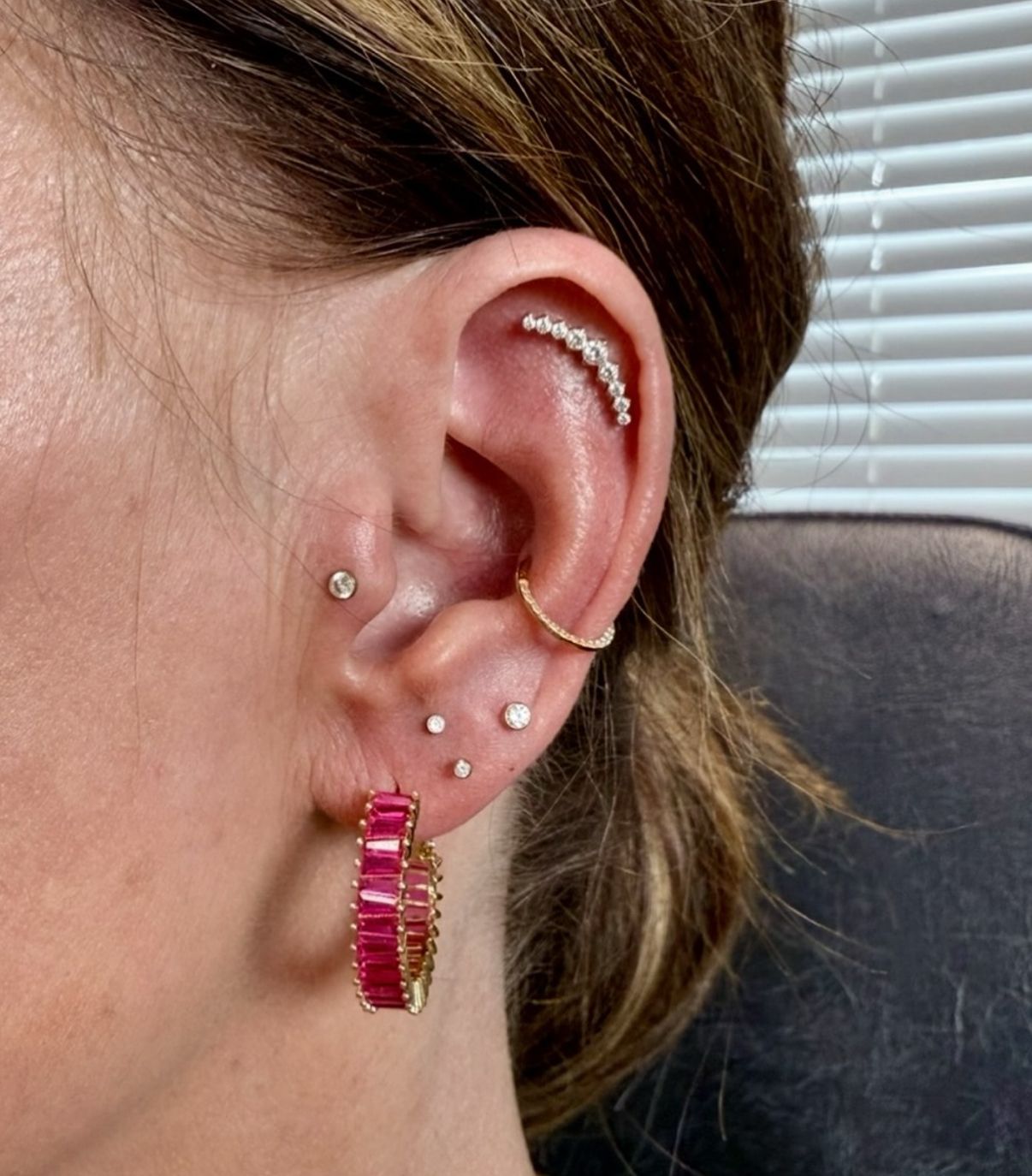 Ear with multiple piercings, including hoop earrings and a curved bar.