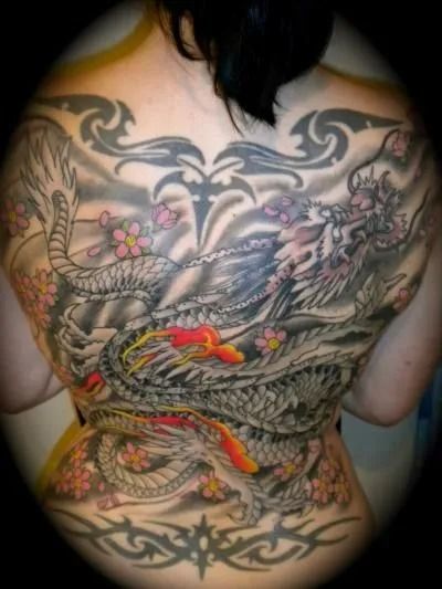 Back tattoo of a gray dragon, red fish, and flowers. Tribal patterns at top and bottom.