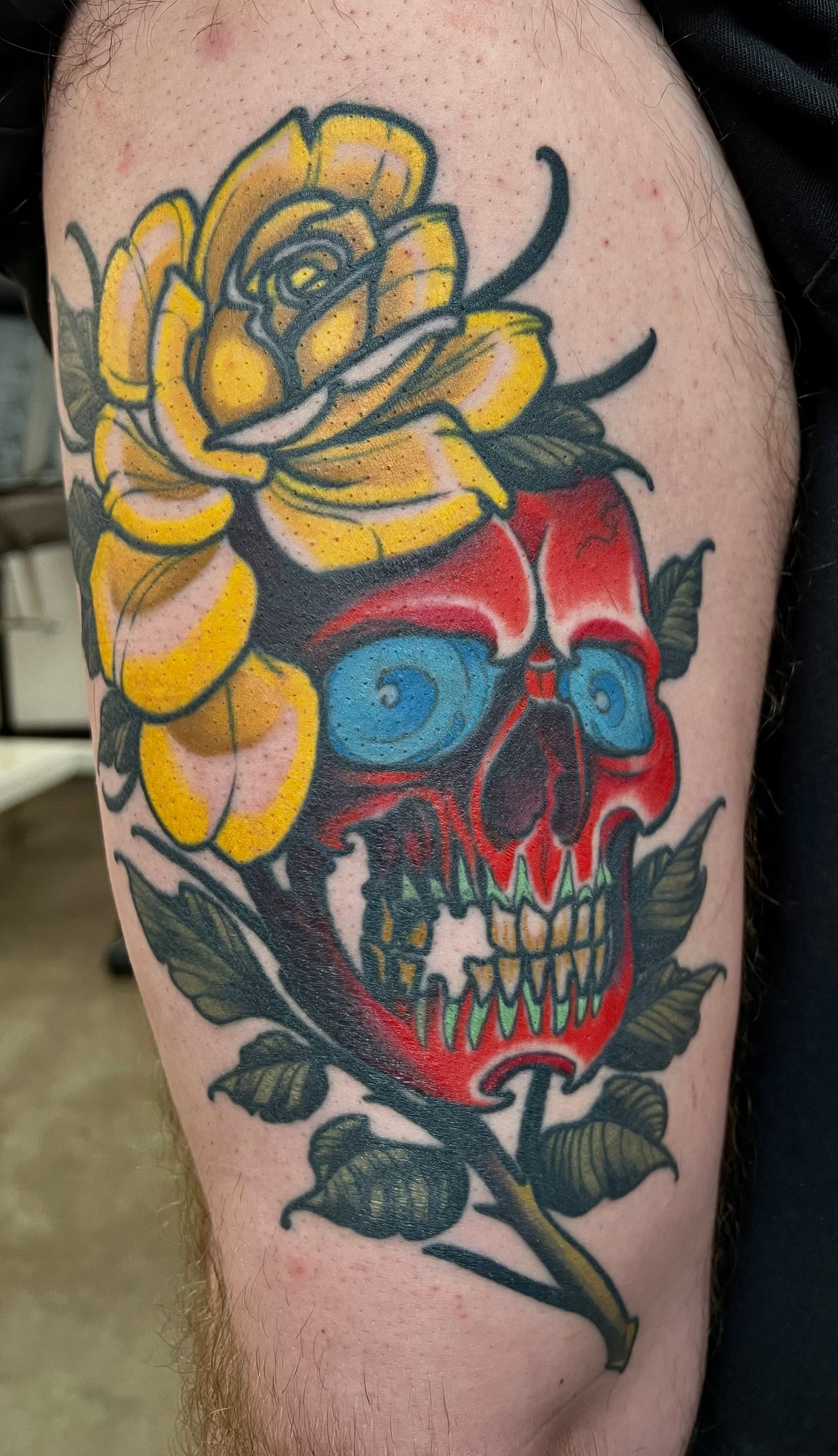 A tattoo of a red skull with yellow flowers
