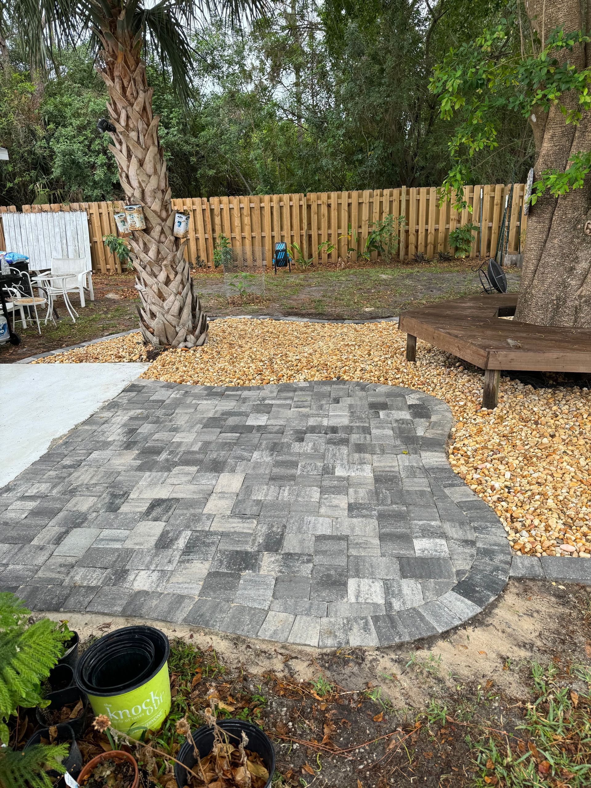 A backyard with a brick patio and a wooden deck.