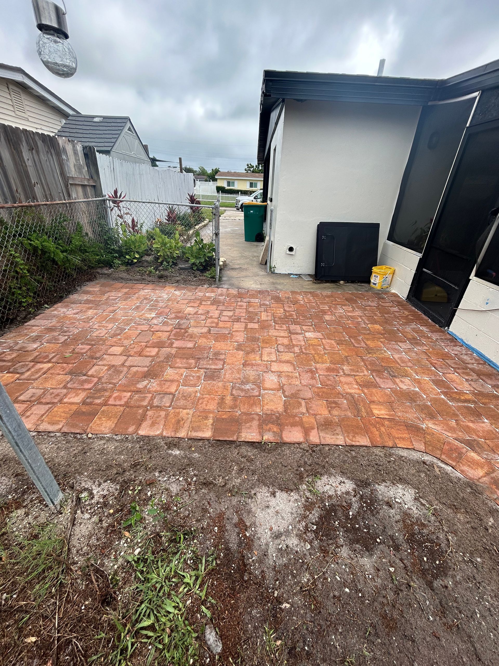 A brick walkway is being built in the backyard of a house.
