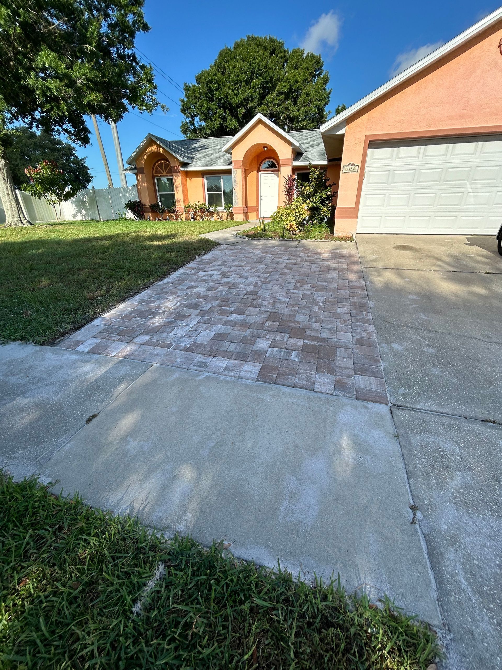 A brick driveway leading to a house with a garage.