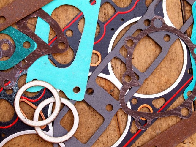 Assorted colorful metal and rubber gaskets and rings piled together on a brown surface