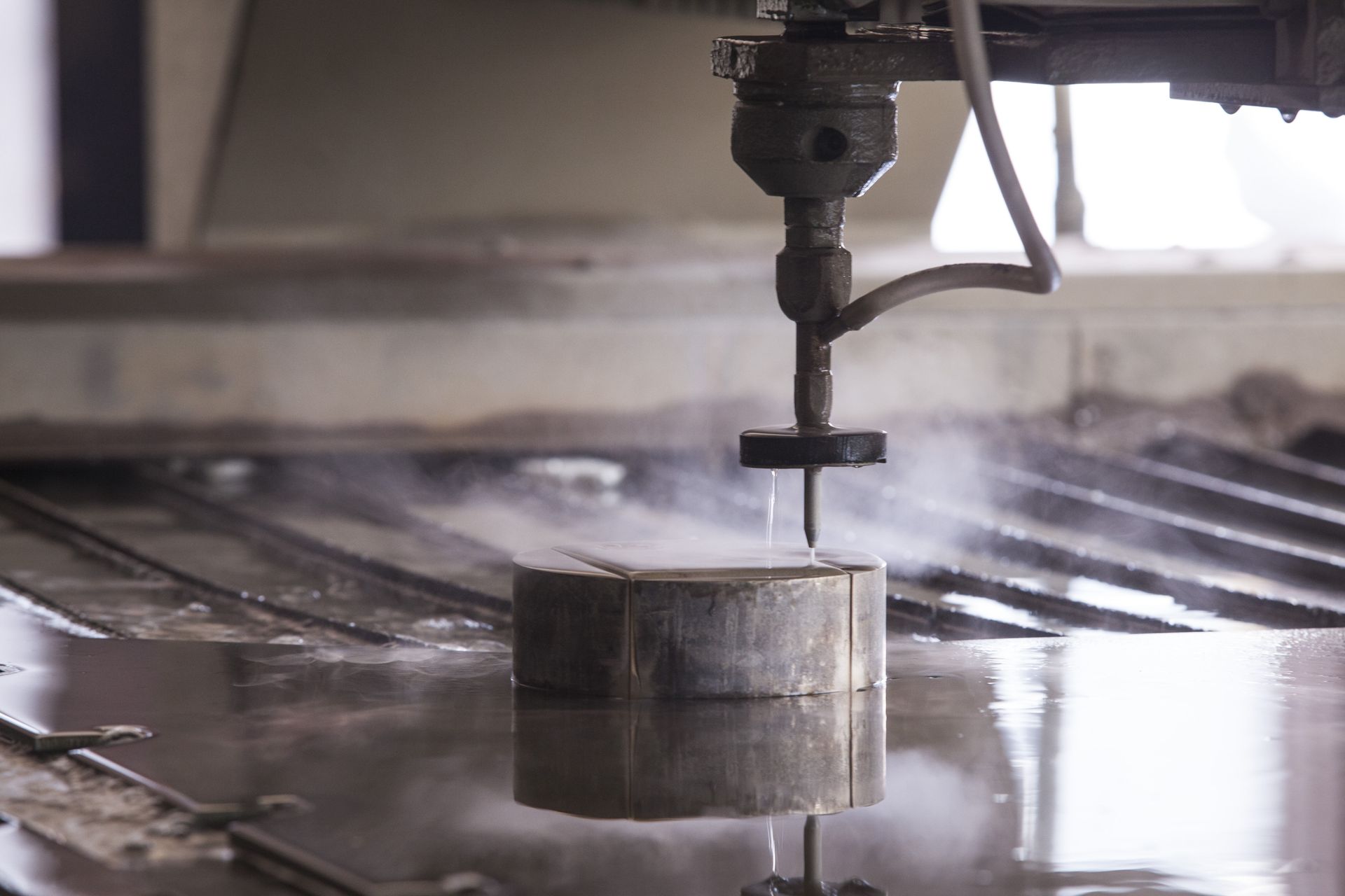 Water jet cutting metal block on a wet industrial machine bed