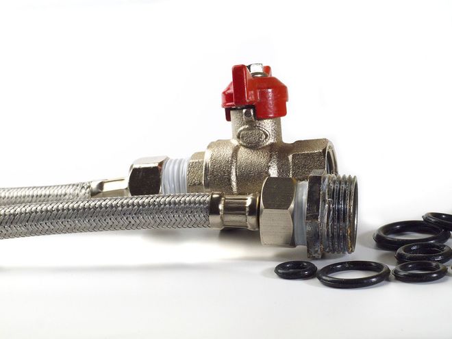 Red-handled valve attached to braided hose, with several black O-rings beside it.