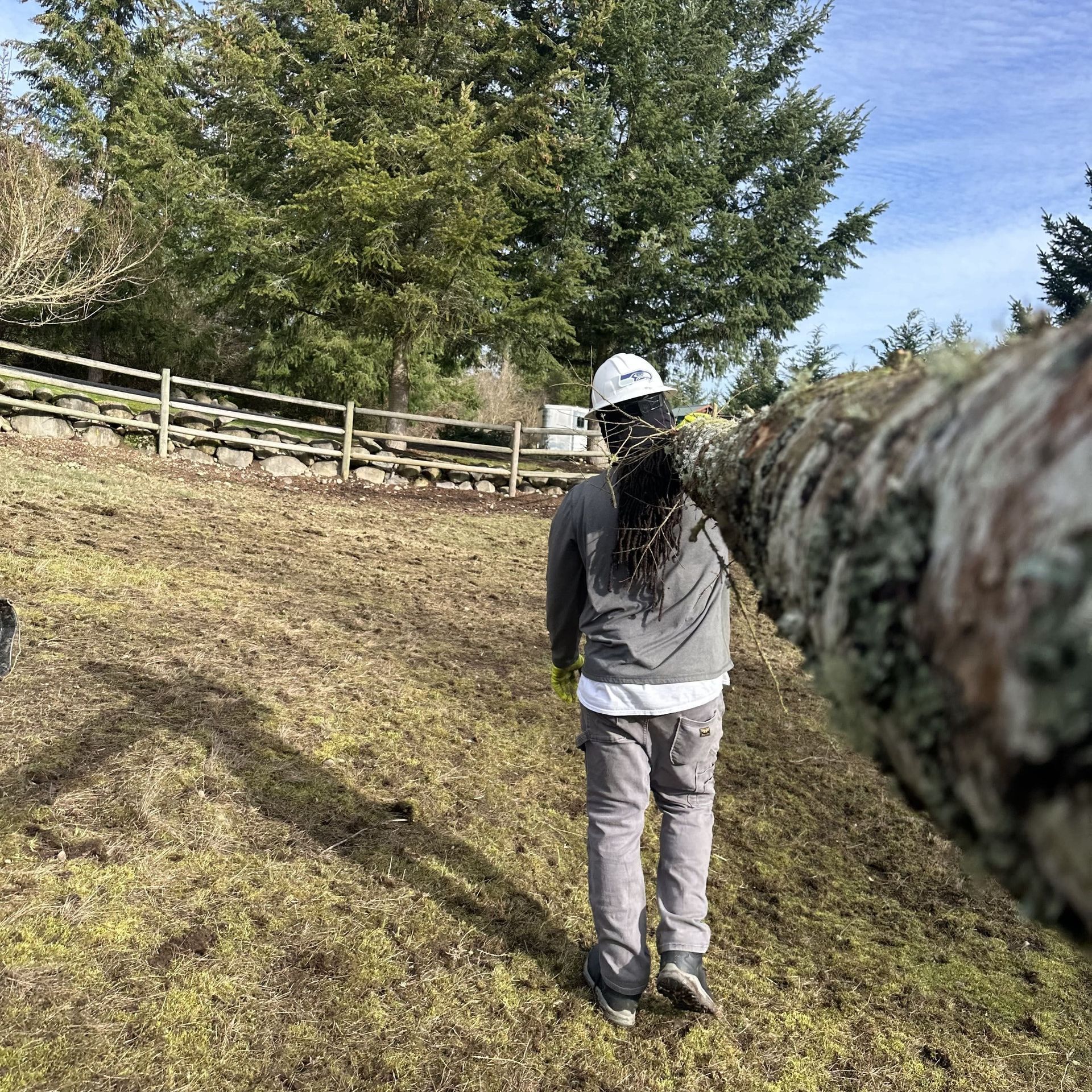 A woman is standing in a field next to a fence.