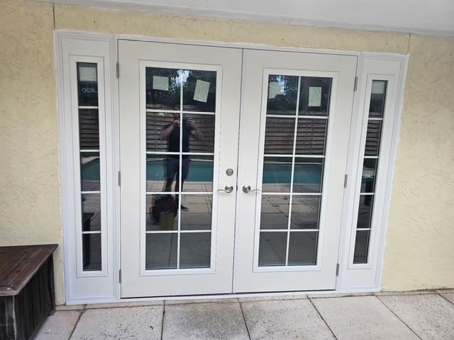 White French doors with glass panes and sidelights on a beige stucco wall
