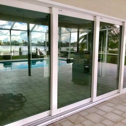 Sliding glass doors reflecting a poolside patio and palm trees
