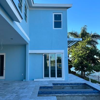 Modern blue two-story house with sliding glass doors and a small backyard pool