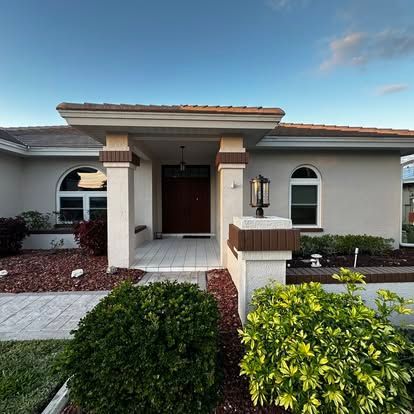 Modern single-story house exterior with white stucco, dark front door, and landscaped front yard
