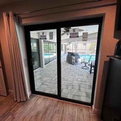 Sliding glass doors open to a covered patio with tiled floor, chairs, and a pool beyond.