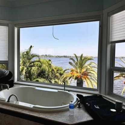 Bathroom with a large soaking tub overlooking palm trees and a waterfront view