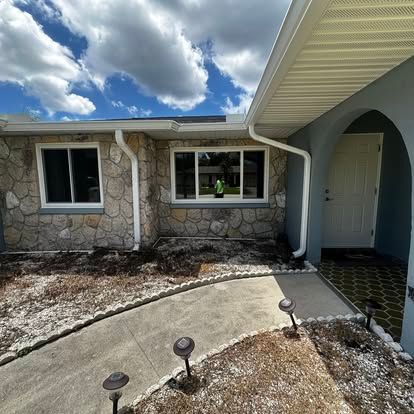 Stone house exterior with windows, arched entry, and front walkway under a cloudy sky