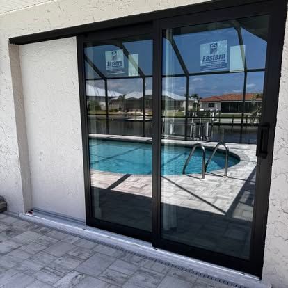 Black-framed sliding glass doors opening to a pool patio with blue water and metal handrails