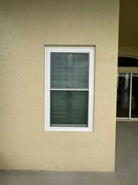 Beige exterior wall with a white-framed window and dark glass pane.