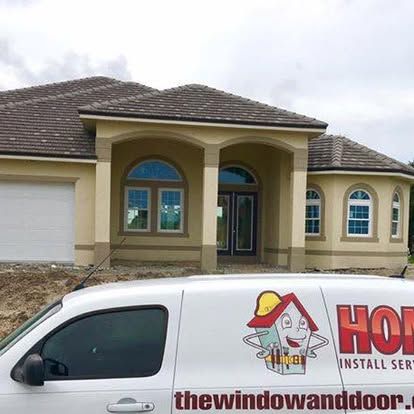 House exterior with tan stucco, arched windows, and a white service van parked in front.