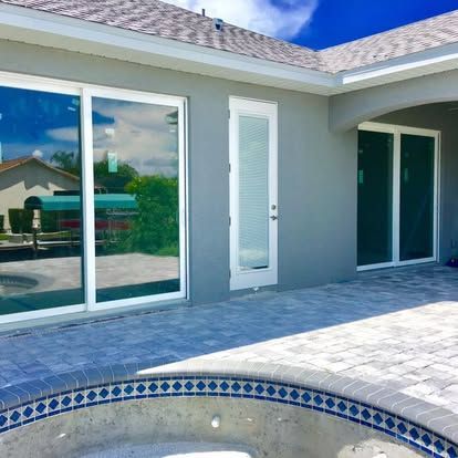 Backyard patio with sliding glass doors and a small tiled pool under a bright blue sky